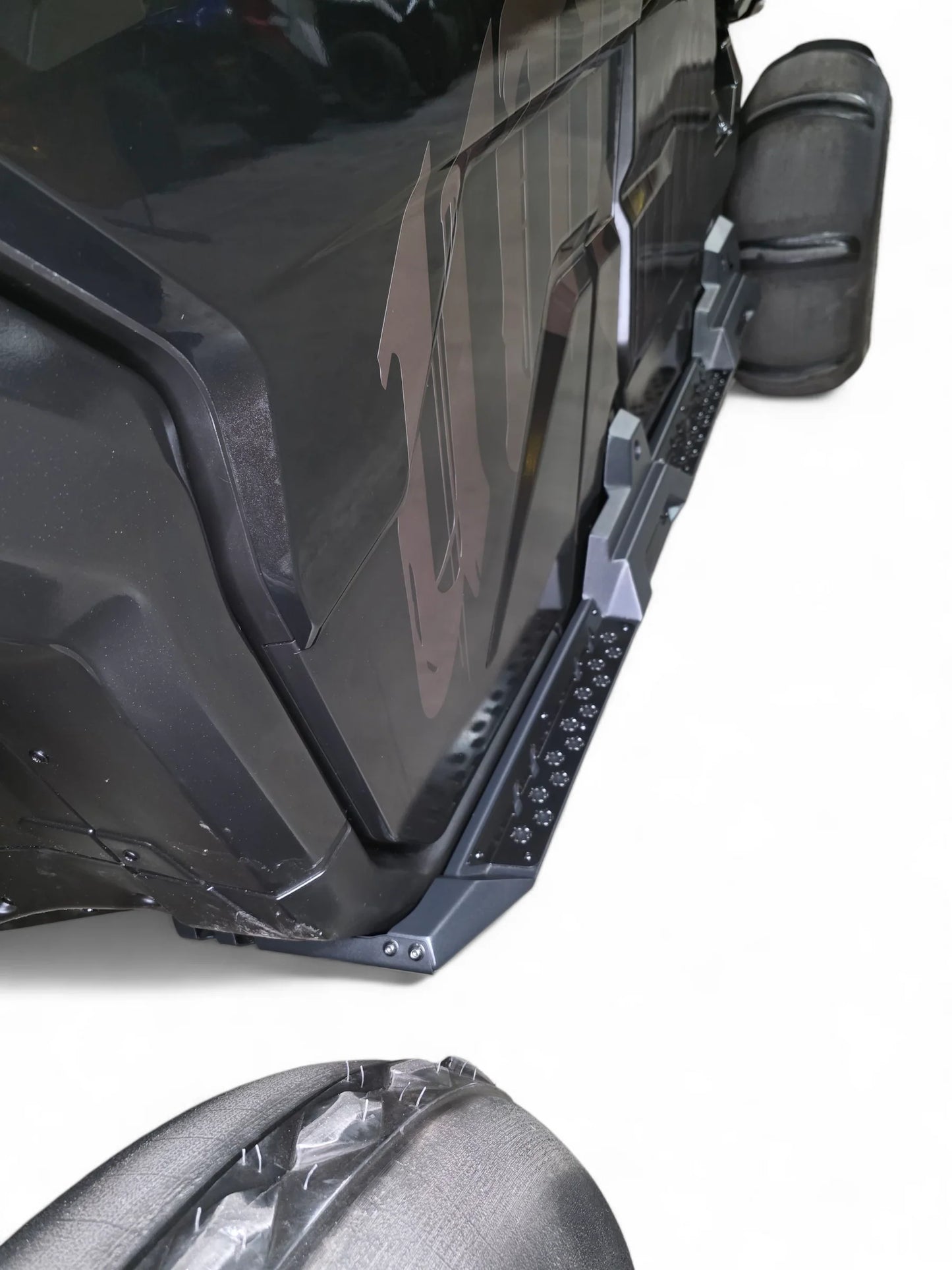 Close-up of a black vehicle with a prominent logo on a white background