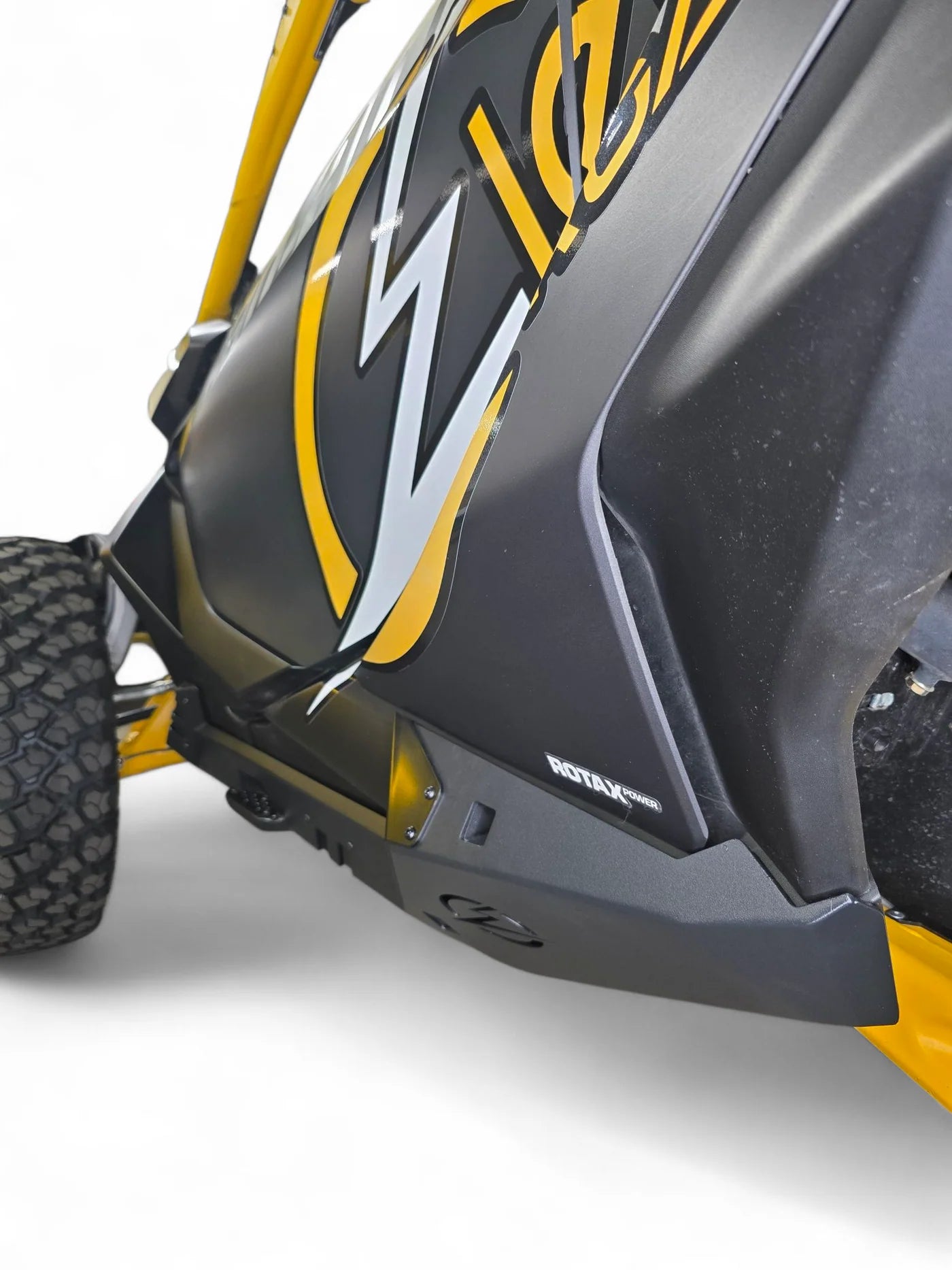 Close-up of a black and yellow off-road vehicle with a prominent logo on a white background
