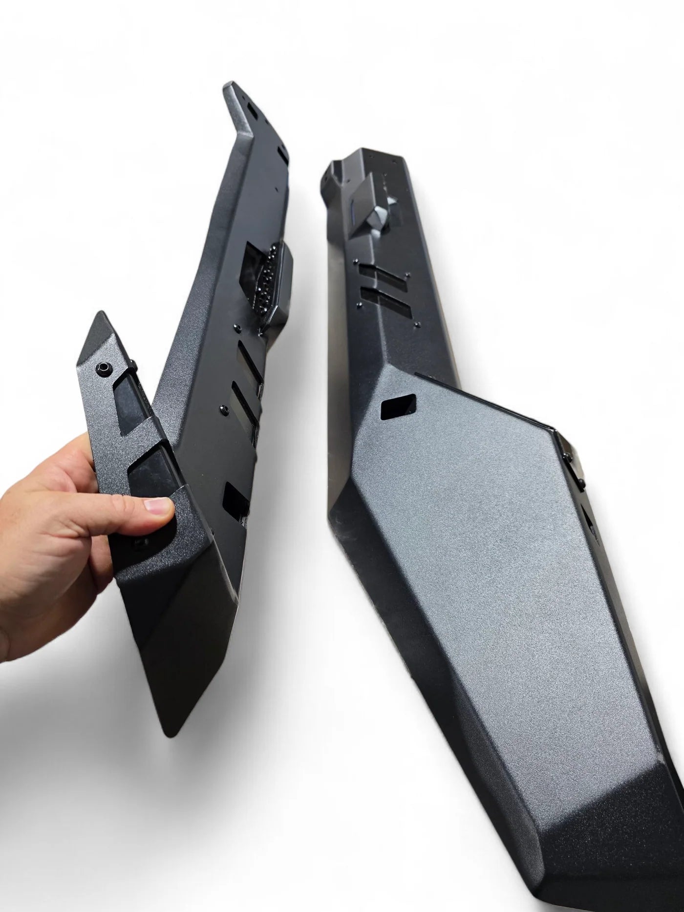 Black metal bracket being held by a hand on a white background