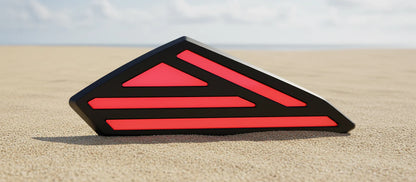 Black and red geometric object on a sandy surface with a blurred background