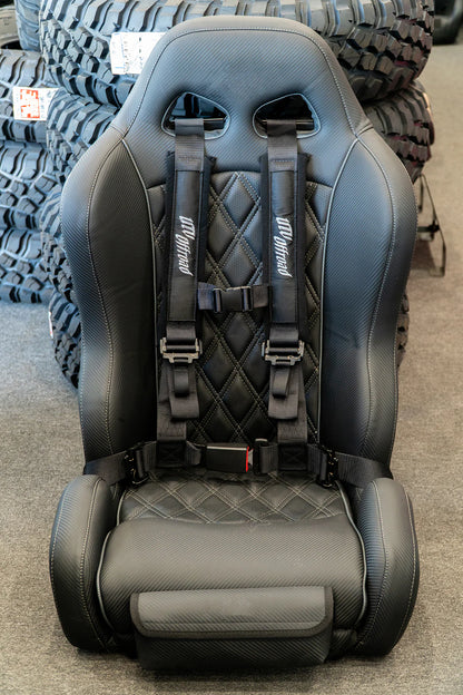 Black car seat with seat belts on a gray floor with tires in the background