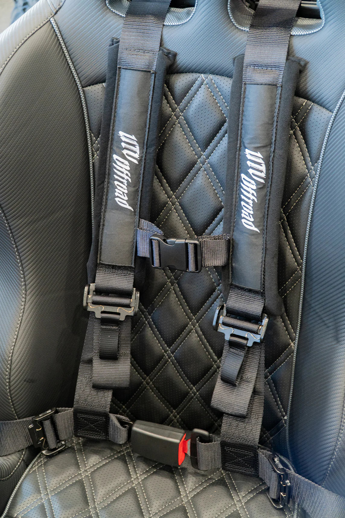 Gray car seat with a detailed harness system on a gray car interior.