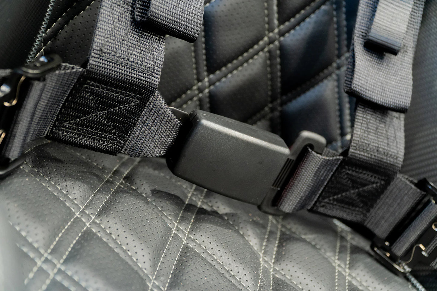 Close-up of a gray quilted bag with black straps and hardware.