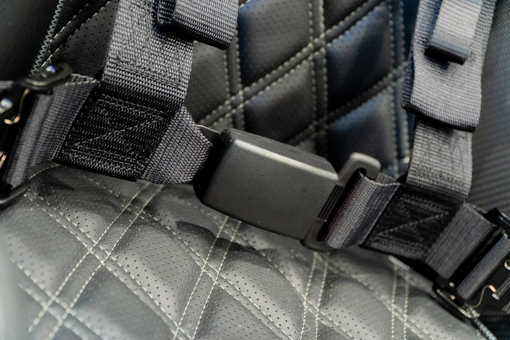 Close-up of a gray quilted bag with black straps and hardware.