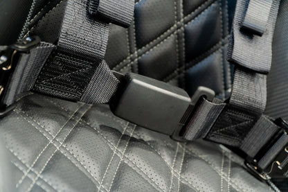 Close-up of a gray quilted bag with black straps and hardware.