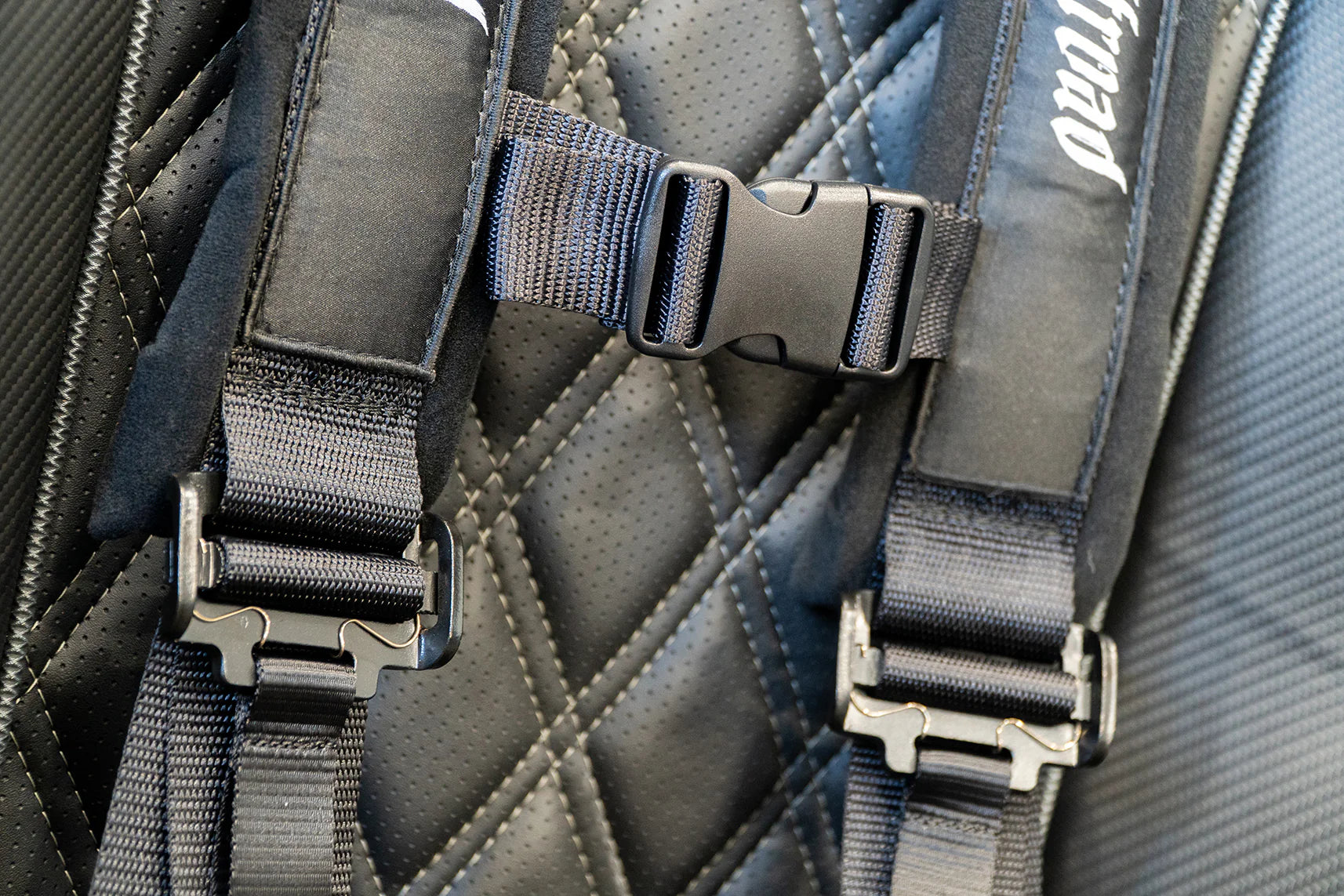 Close-up of a backpack with straps and a brand logo on a textured fabric background