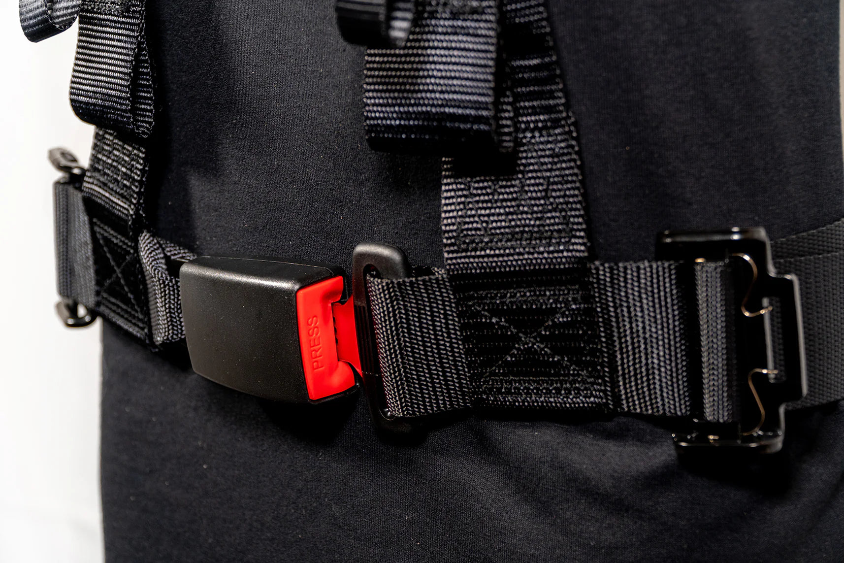 Close-up of a black harness with a red buckle on a plain background