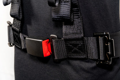 Close-up of a black harness with a red buckle on a plain background