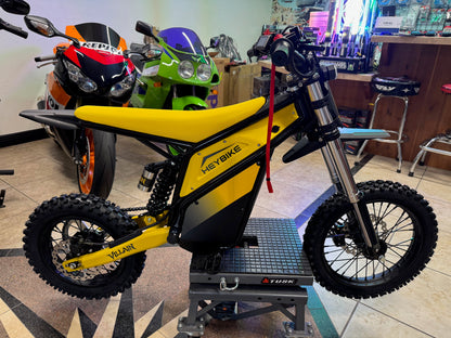 Yellow and black electric bike on display in a showroom with other bikes in the background.