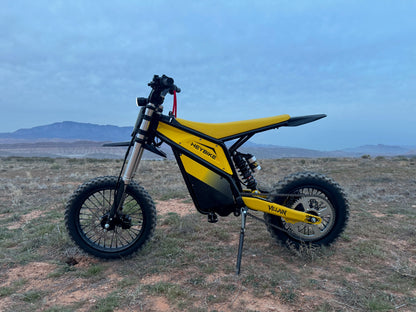 Yellow electric bike on a grassy field with mountains in the background