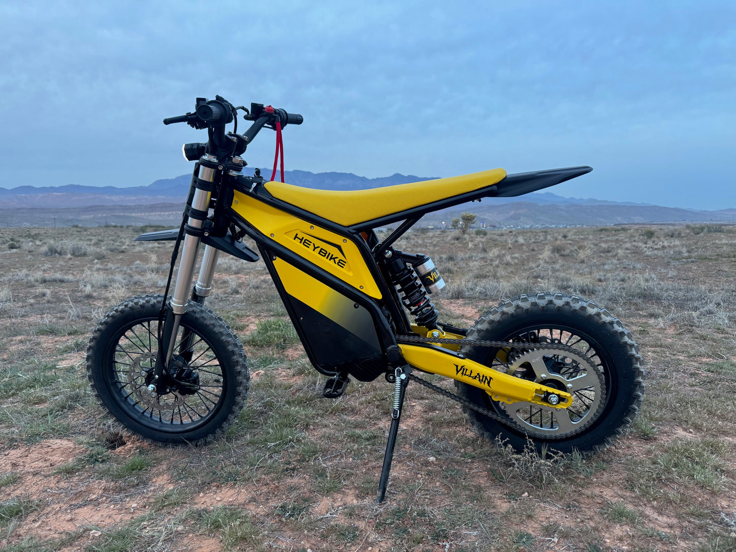 Yellow and black electric bike on a desert landscape with mountains in the background
