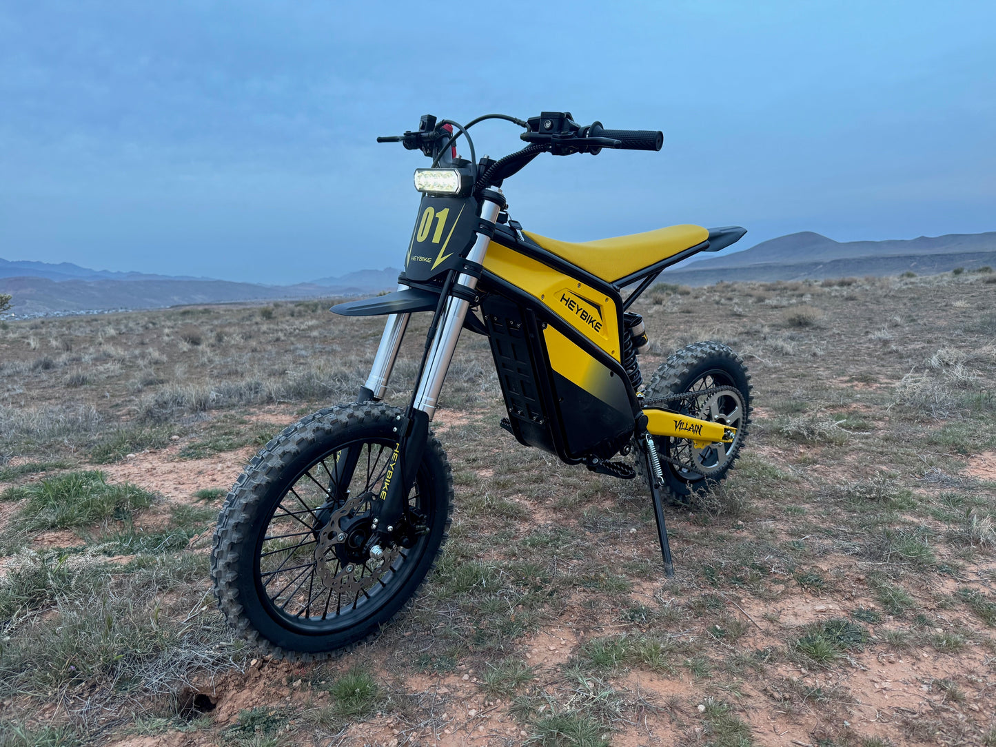 Yellow and black electric bike on a desert landscape with mountains in the background