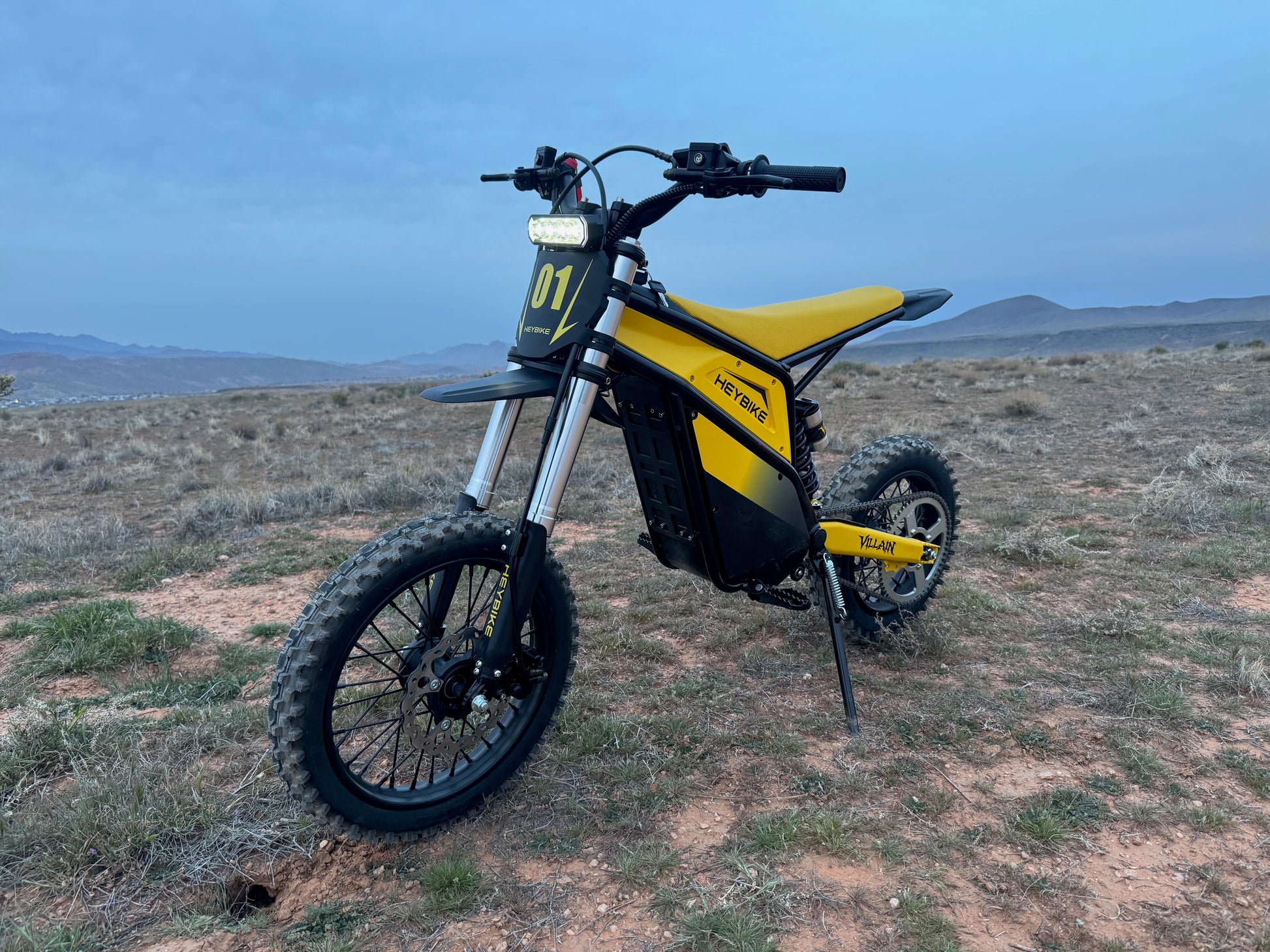 Yellow and black electric bike on a desert landscape with mountains in the background