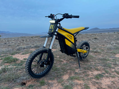 Yellow and black electric bike on a desert landscape with mountains in the background
