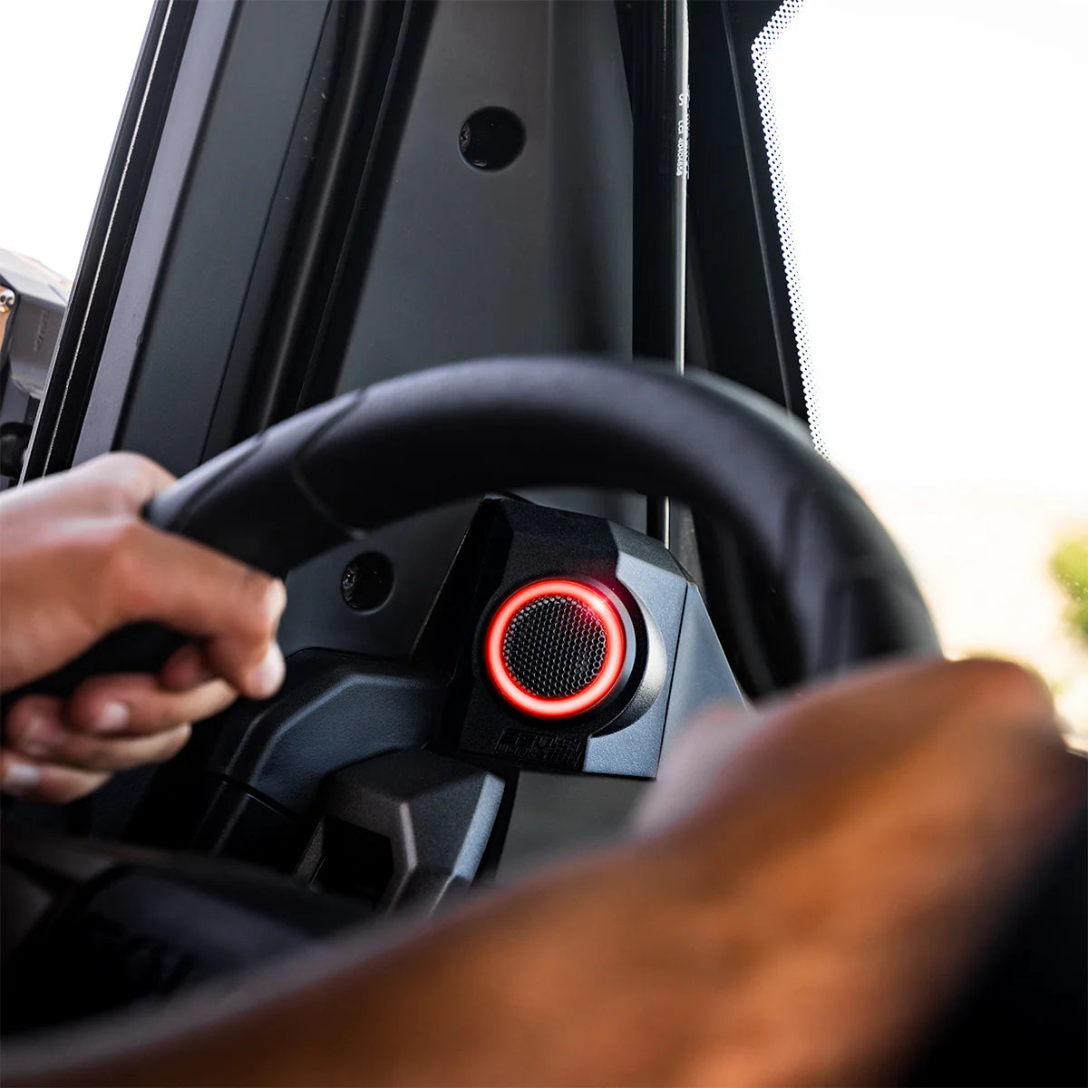 Steering wheel with red center and hand on it inside a vehicle