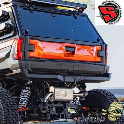 Close-up rear view of a black Polaris off-road vehicle with a bright orange rear tailgate panel and custom black bumper. Visible branding includes Polaris on the tailgate and HCR on the suspension components.