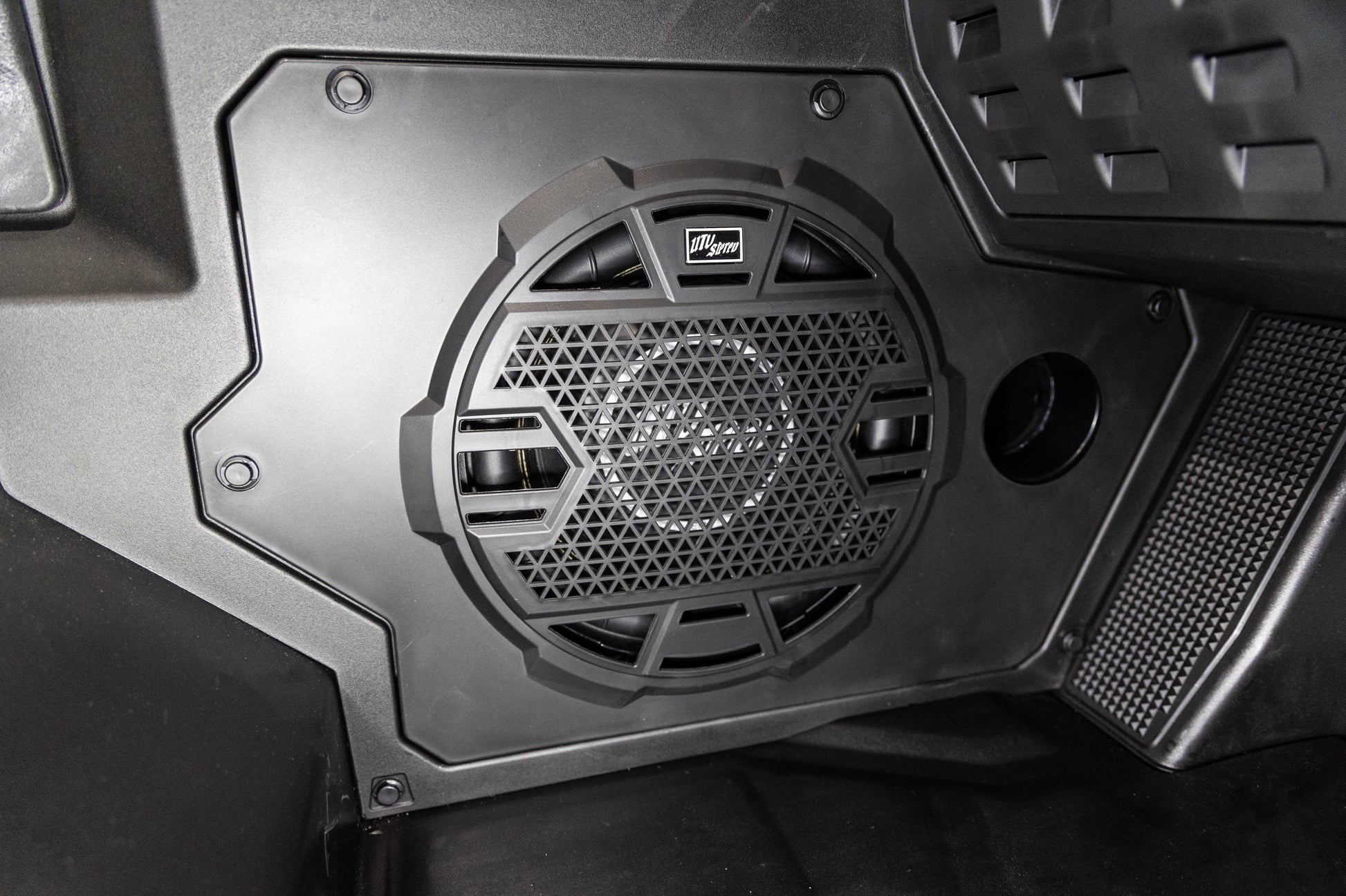 Close-up of a speaker grille with brand logo on a vehicle interior.