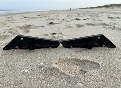 Two black metal brackets on a sandy beach with ocean in the background