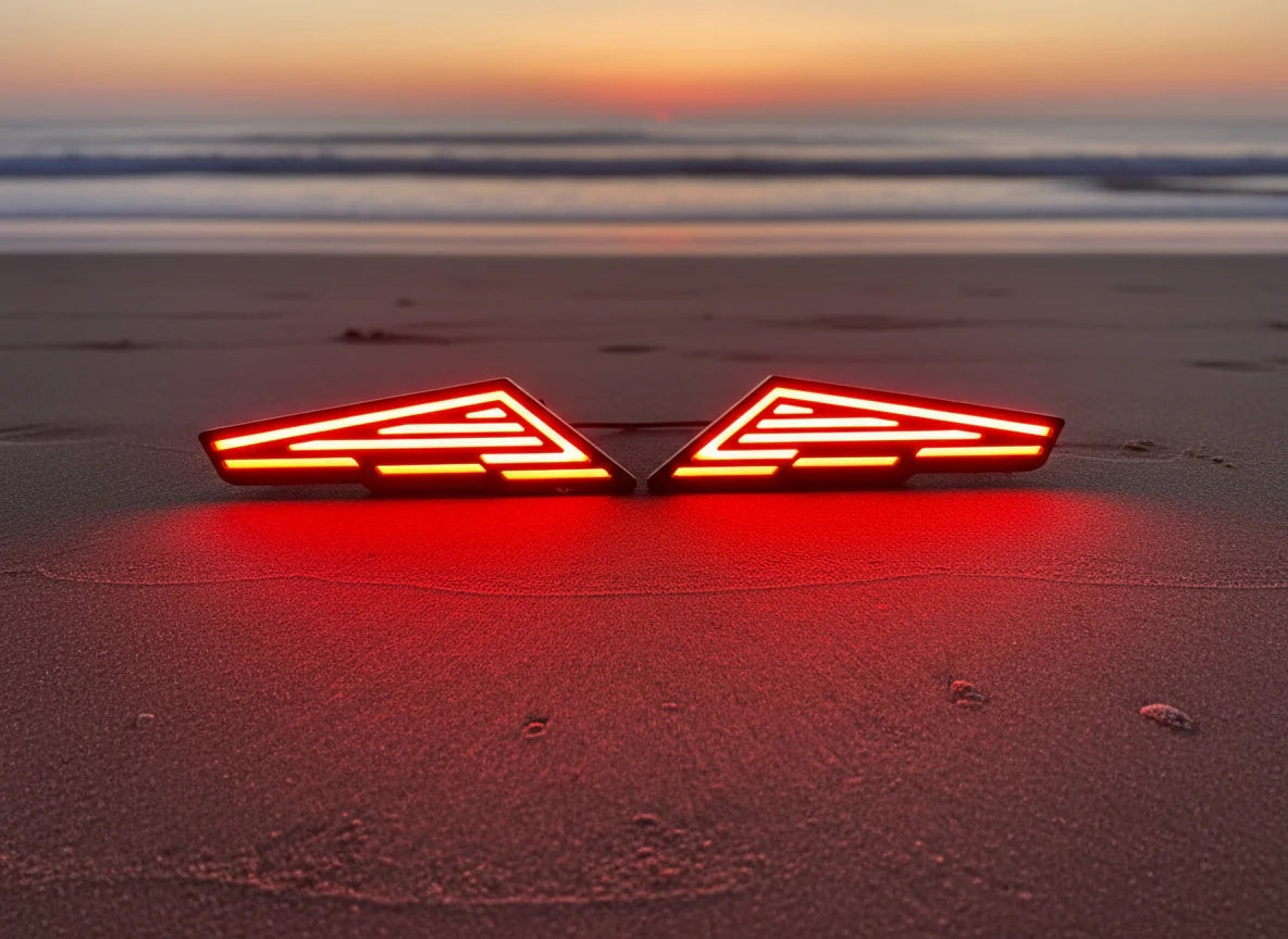 Two red LED lights on a sandy beach at sunset.