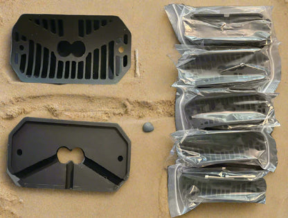 Black metal grates on a cardboard surface with some in clear plastic packaging.