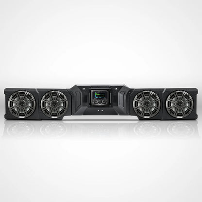 A black multi-subwoofer home theater speaker system with four large woofers and a central control screen, shown on a reflective white studio background.