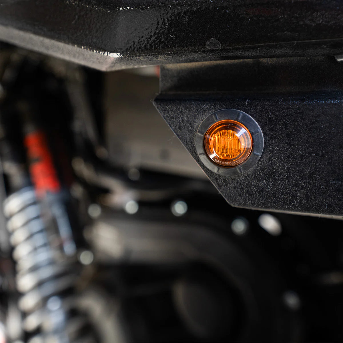 Close-up of a motorcycle's orange turn signal light on a blurred background