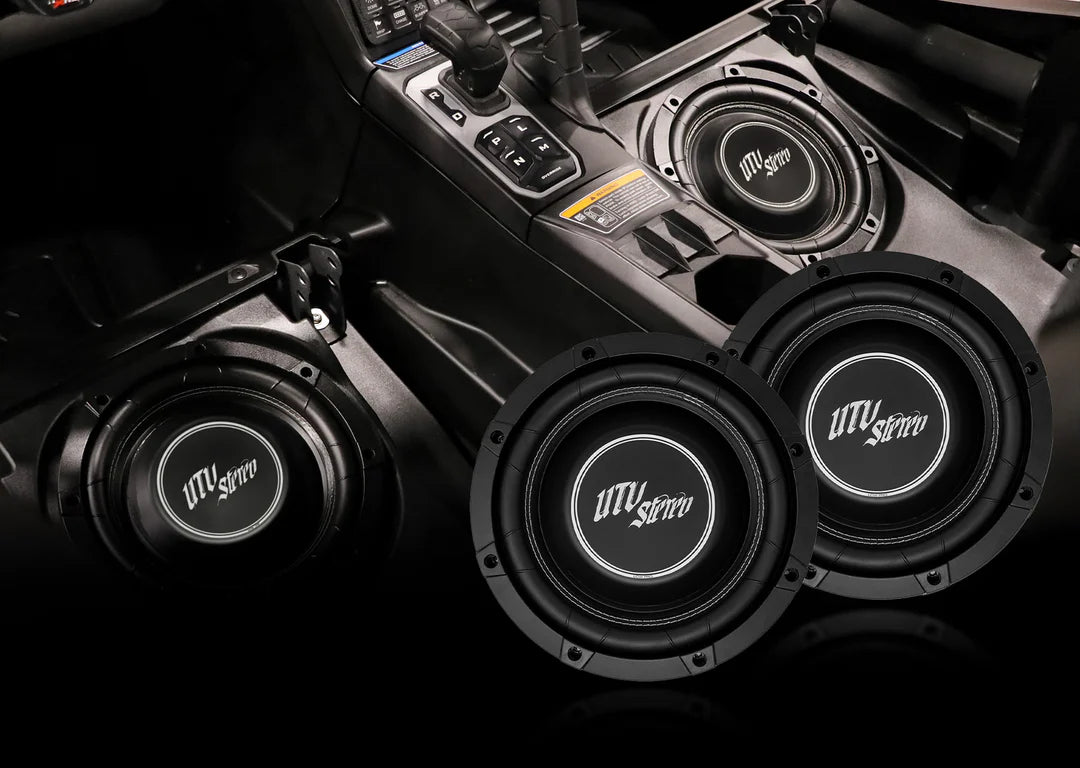 Four subwoofers with 'UTV Stereo' branding installed in a vehicle's dashboard.