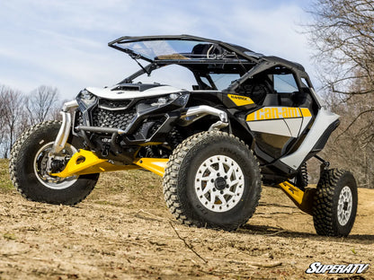 Yellow and black off-road vehicle on a dirt field with trees in the background
