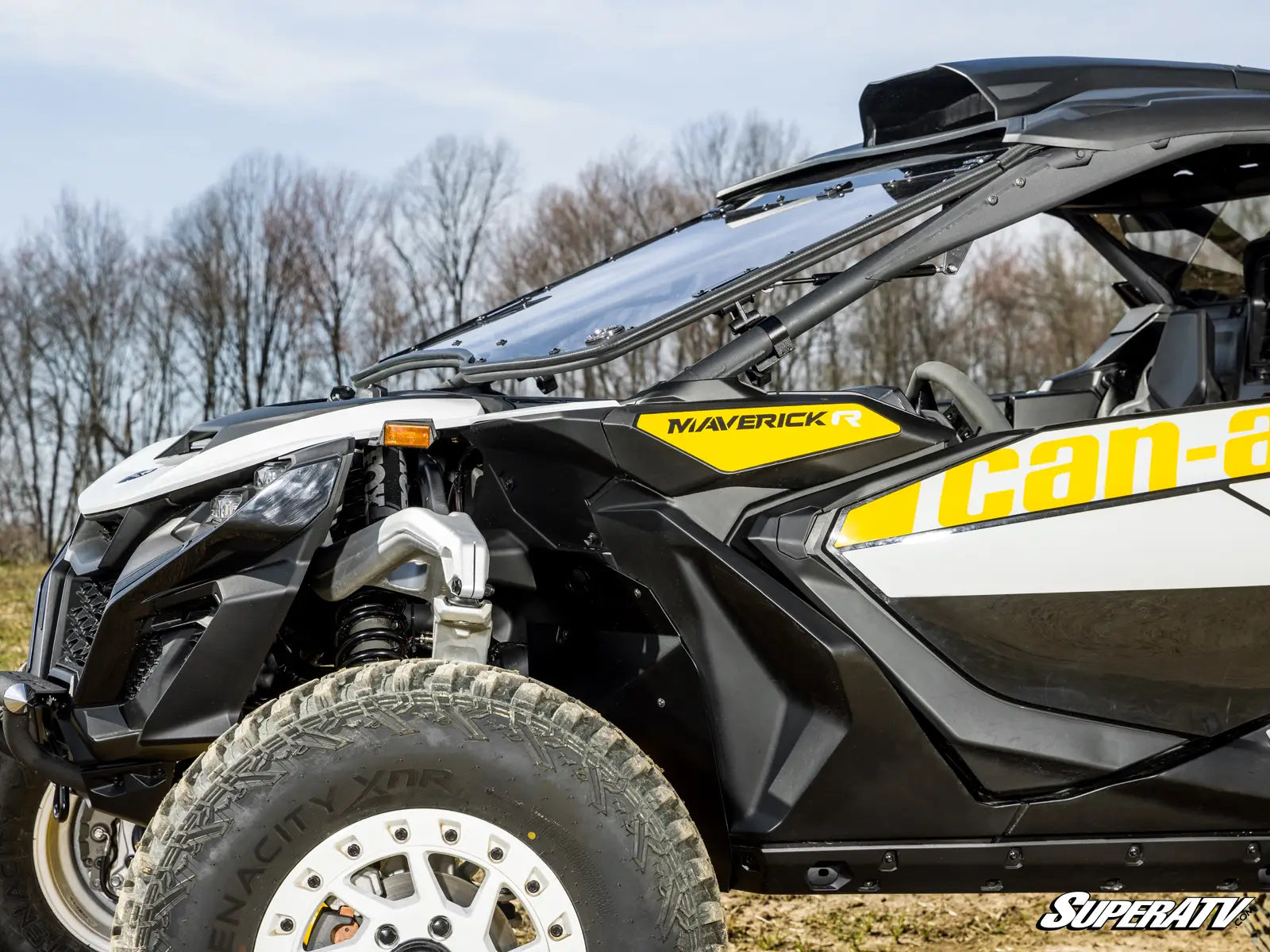 Can-Am Maverick SuperATV off-road vehicle in a natural setting with trees and open sky.