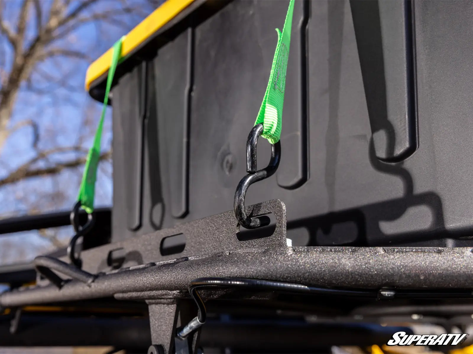 Close-up of a SuperATV product with a hook and green strap on a vehicle.