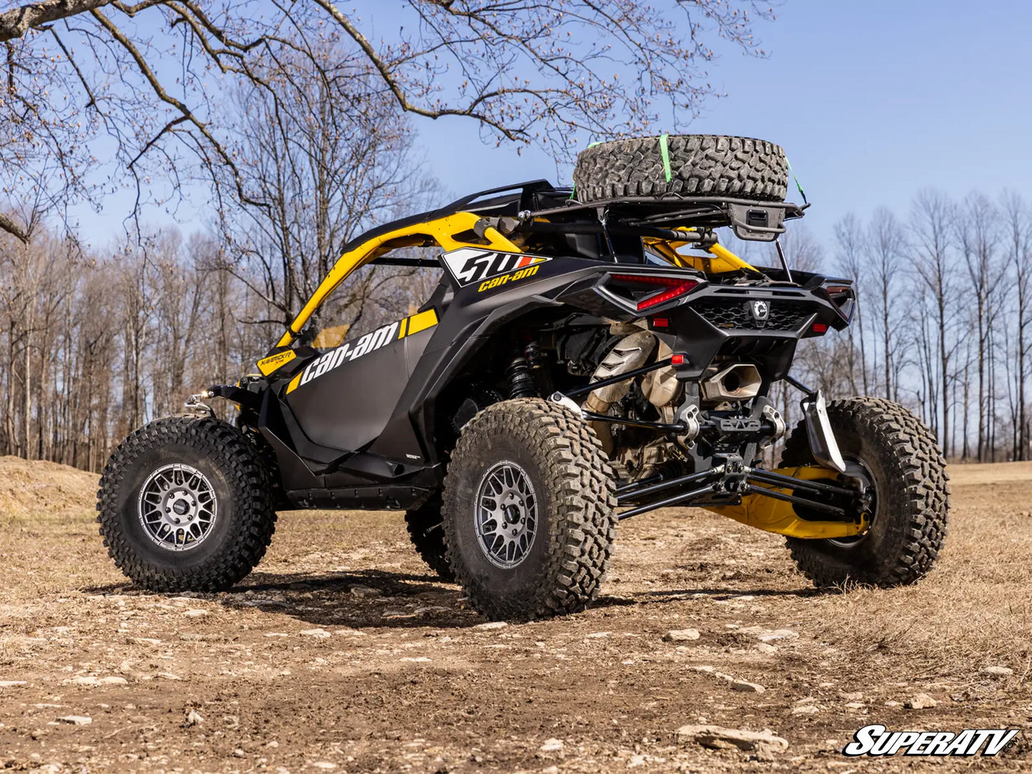 Yellow and black off-road vehicle on a dirt path with trees in the background