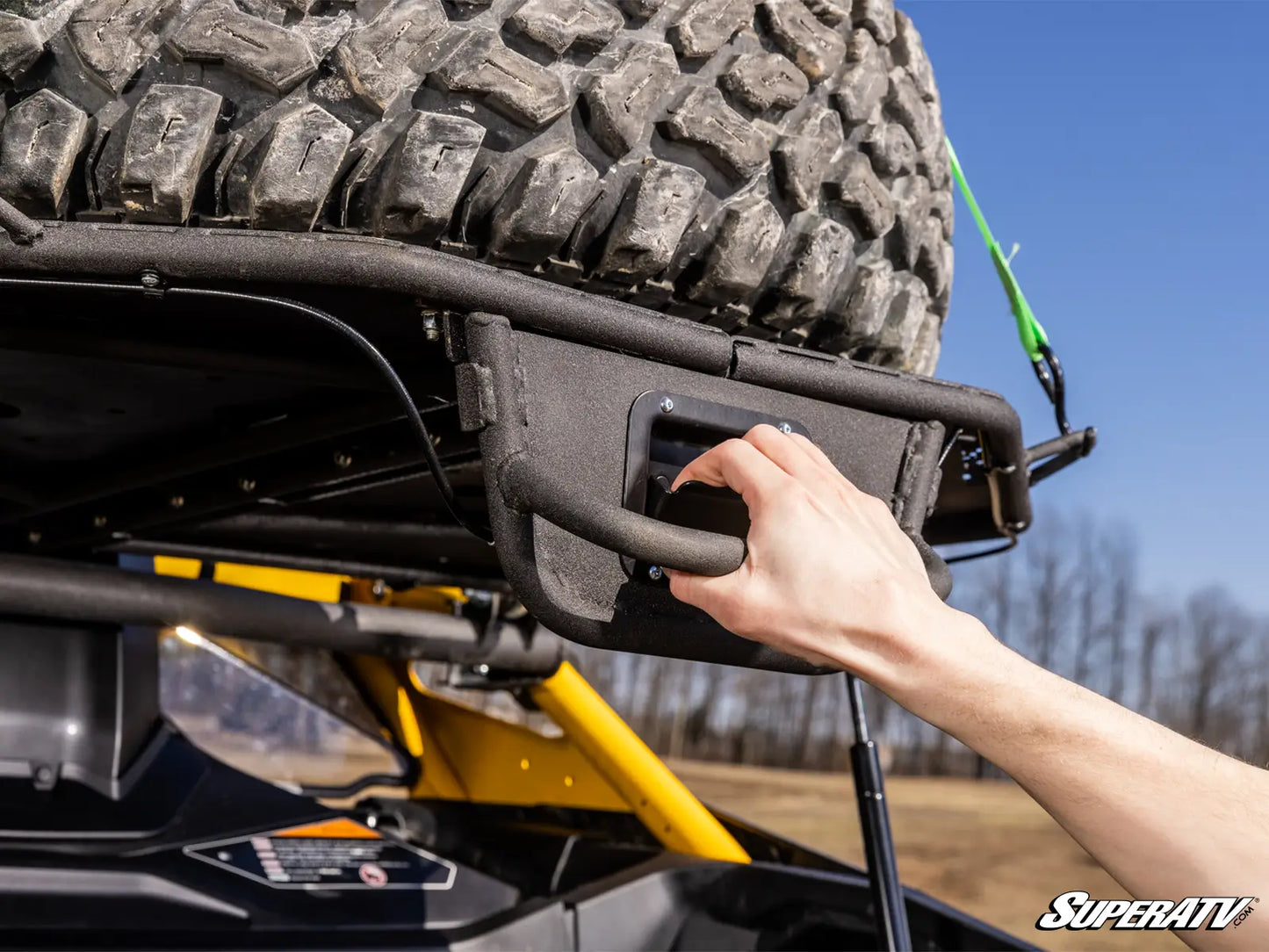 Hand adjusting a vehicle bumper on an off-road vehicle with a SuperATV logo.