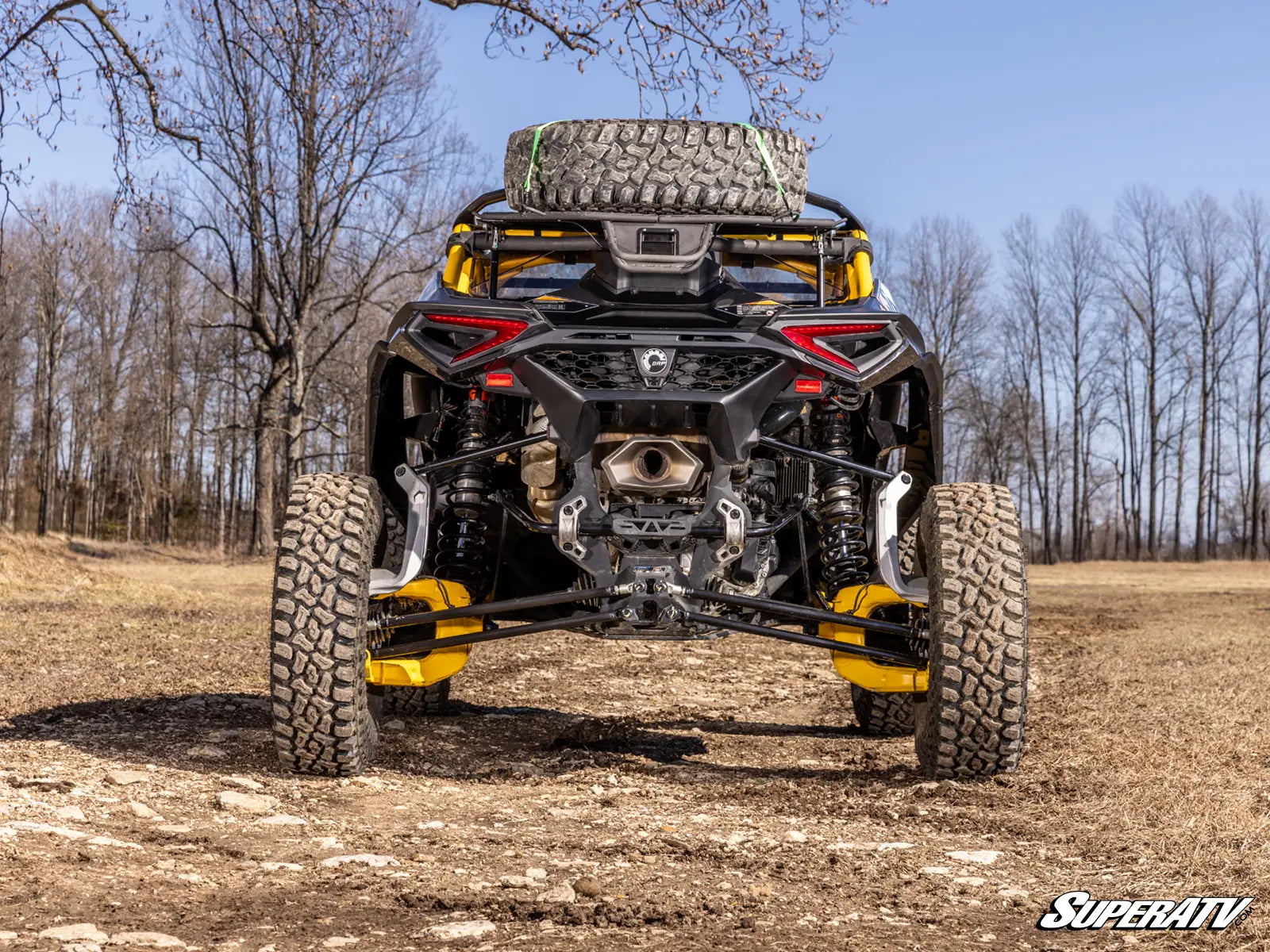 Back view of a large off-road vehicle with a spare tire on a dirt field.