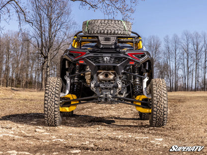 Back view of a large off-road vehicle with a spare tire on a dirt field.