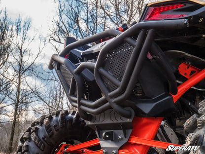 Close-up of a red and black off-road vehicle with a SuperATV bumper in a natural setting.