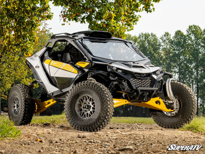 Yellow and black SuperATV off-road vehicle on a dirt path with trees in the background
