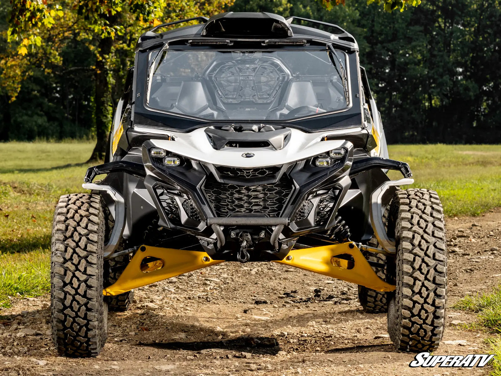 Can-Am Maverick X3 side-by-side vehicle on a dirt path with trees in the background