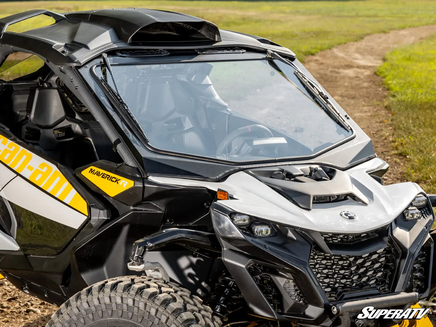 Side view of a Can-Am vehicle on a dirt path with grass in the background