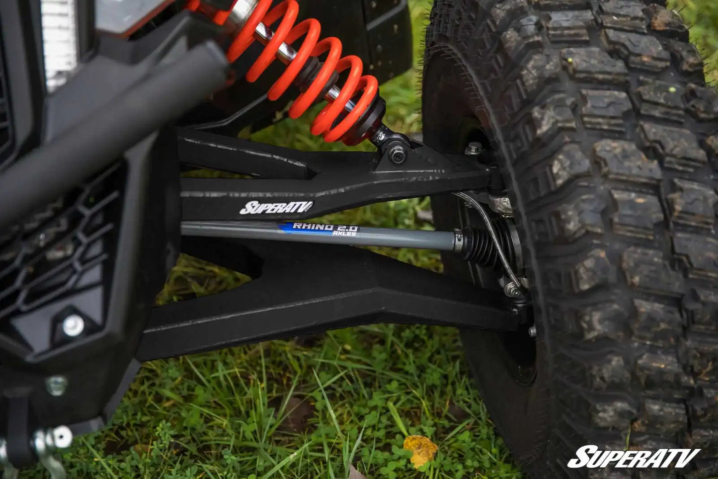 Close-up of SuperATV suspension system on a vehicle with grass in the background