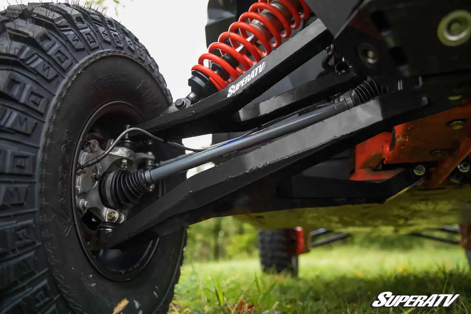 Close-up of a SuperATV vehicle suspension system on grass