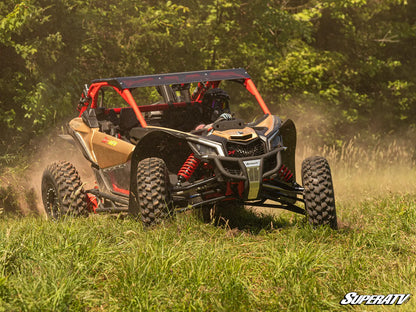 Off-road vehicle driving through a grassy area with trees in the background