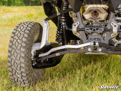 Close-up of a SuperATV suspension system on an ATV in a grassy field.
