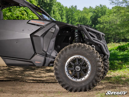 Close-up of a SuperATV vehicle on a dirt path with trees in the background