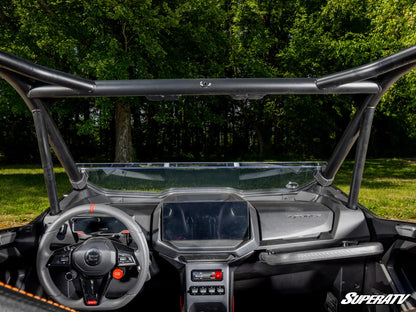 Interior of a SuperATV vehicle with steering wheel and dashboard, surrounded by greenery.
