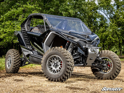 Black SuperATV off-road vehicle on a dirt path with trees in the background