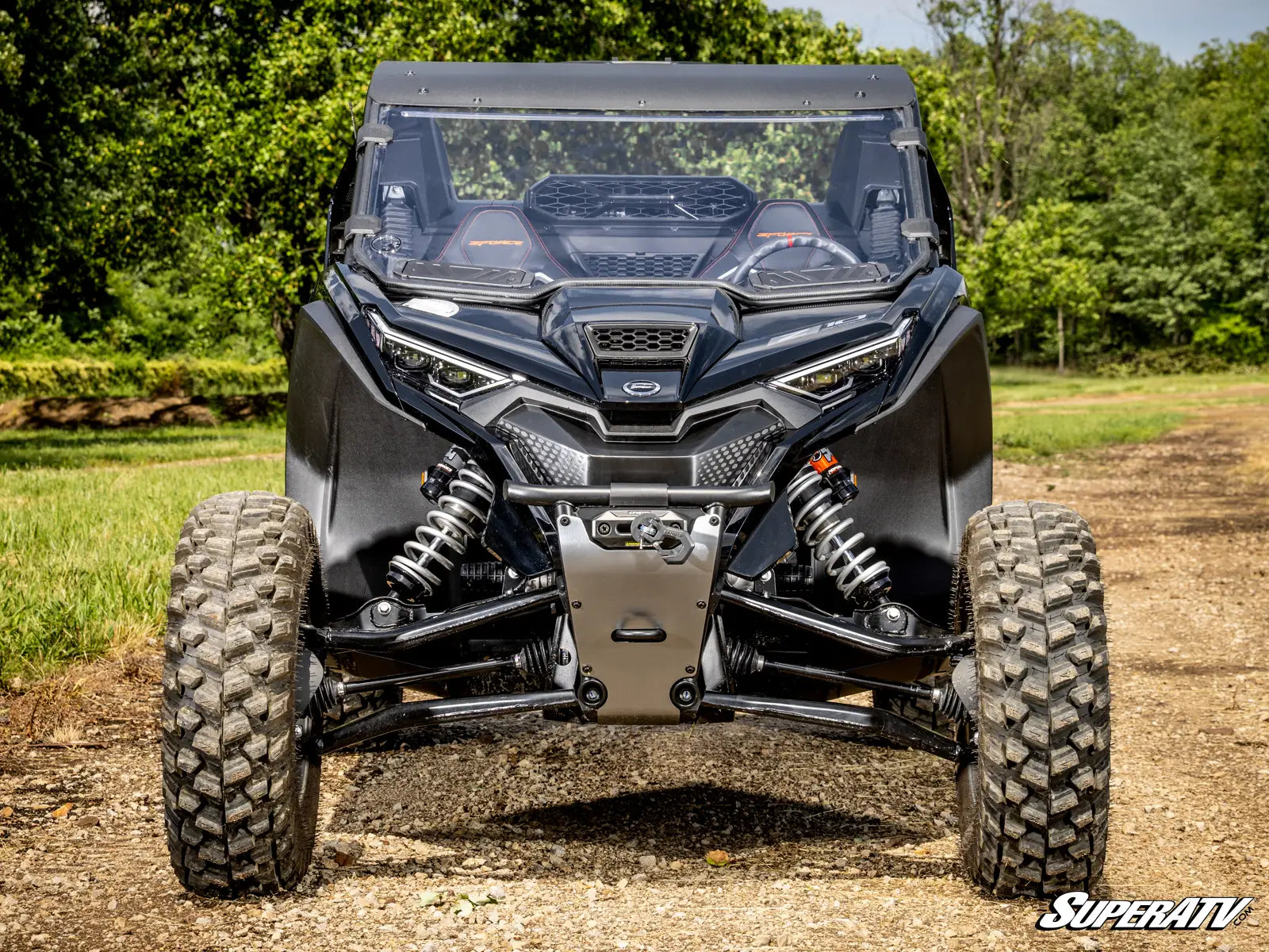 SuperATV vehicle on a dirt road with trees in the background