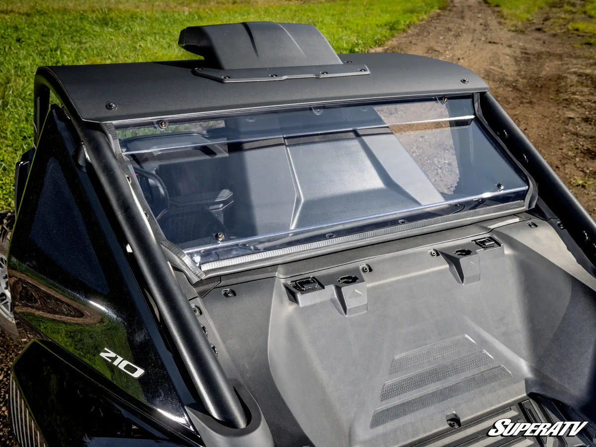 A close-up outdoor shot of the rear cabin area of a black off-road vehicle, showing a clear windshield, dark roof trim, and a gray interior panel. The word 'SUPER ATV' appears in the bottom right corner.