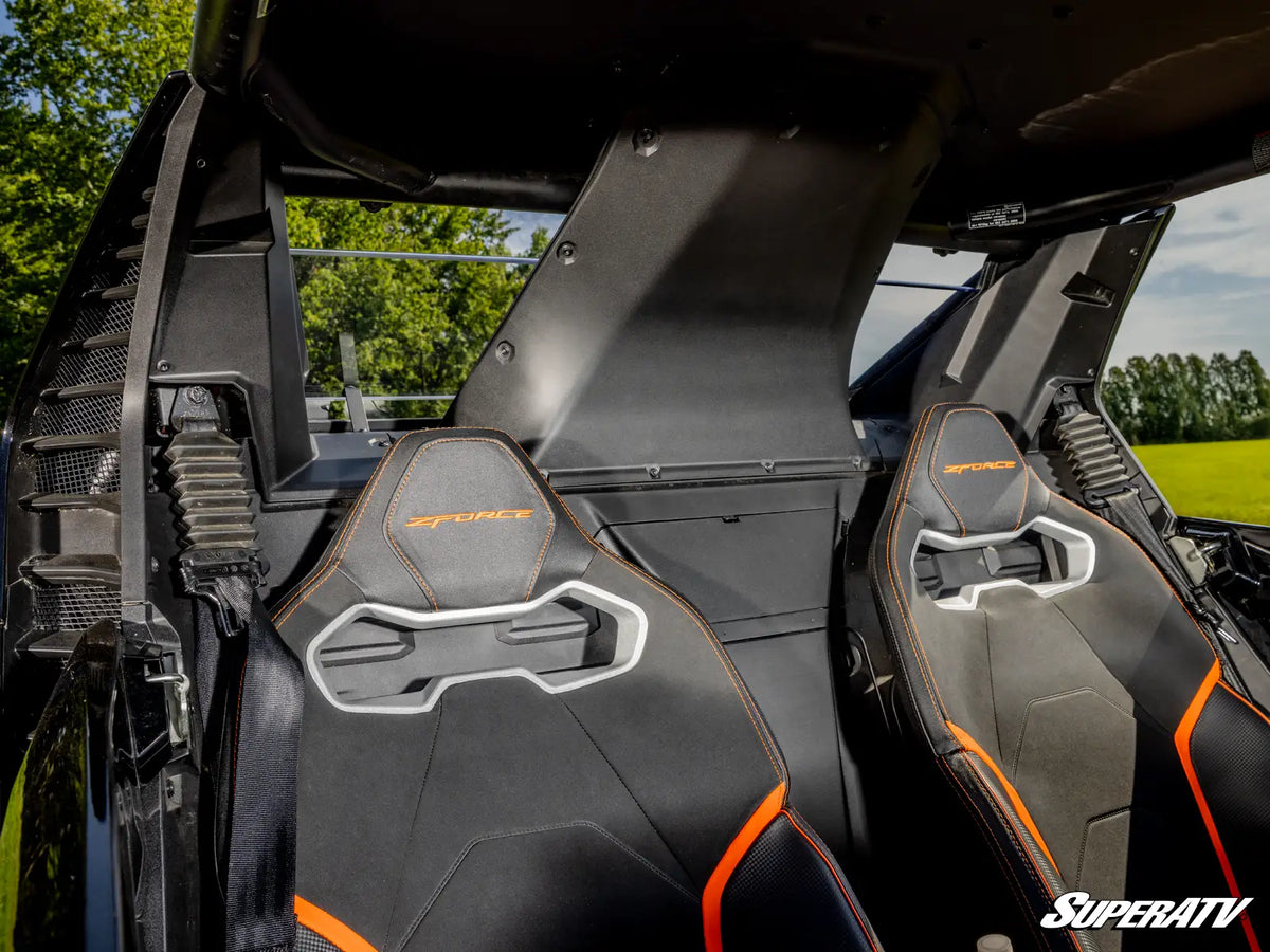 Close-up of the interior of a black and orange supercar, showing the two bucket seats with 'STURM' embroidered on the headrests and a silver license plate frame integrated into the seat.