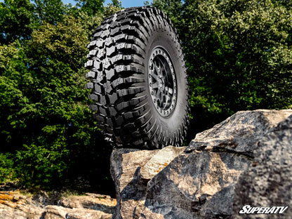 Off-road tire on a rock with a forest background, featuring the SuperATV logo.