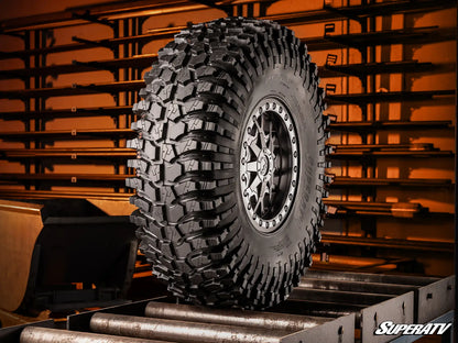 Off-road tire with deep tread pattern on a metal surface, SuperATV branding visible